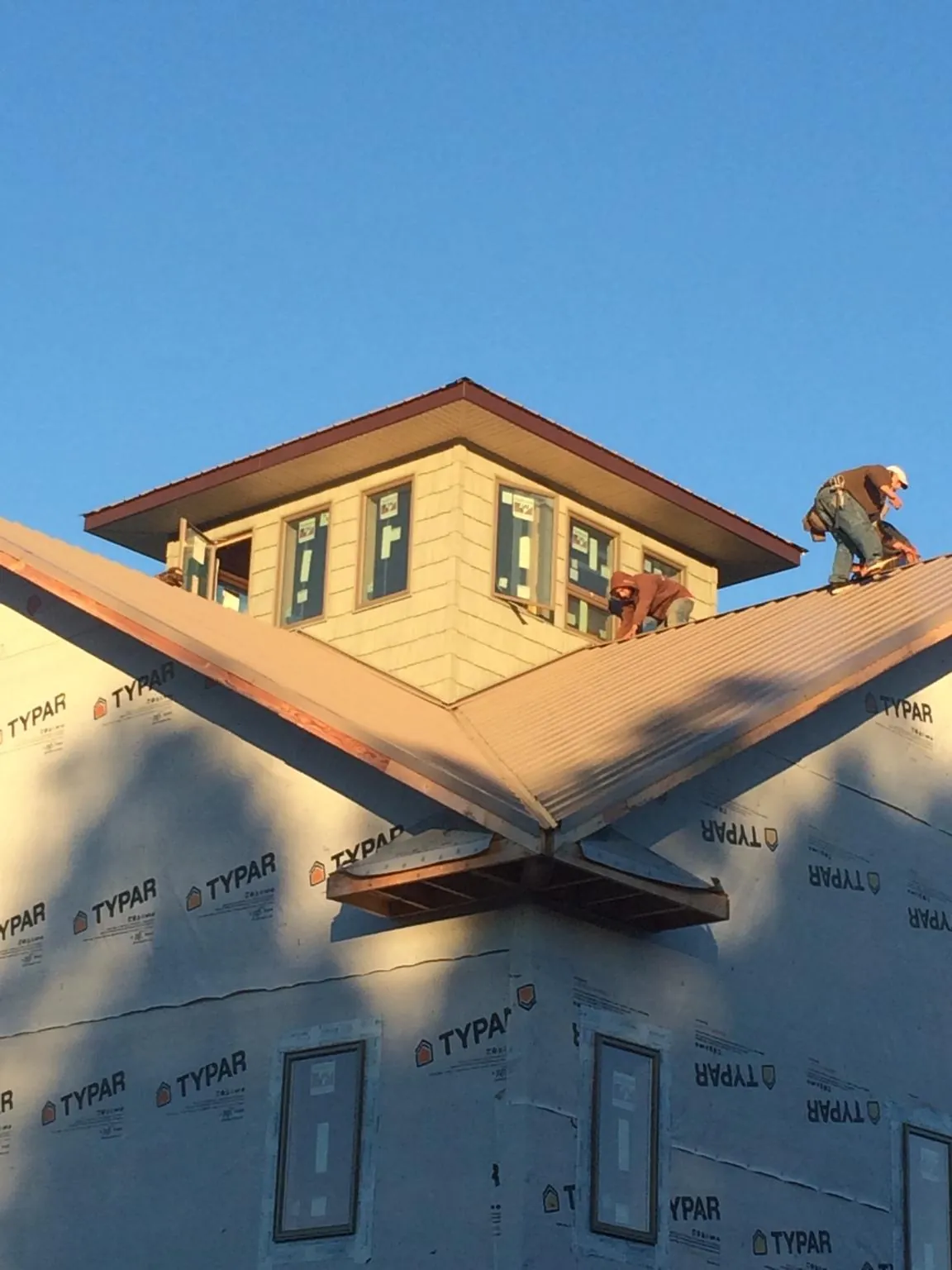 Roofers working around a rooftop cupola on a new metal roof at sunset — Roof Waterproofing in Sun City West by Roofing Brothers